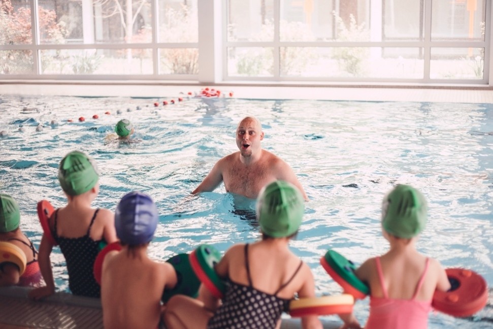 Mädchen mit Schwimmbrille übt mit einer Schwimmlehrerin im Becken